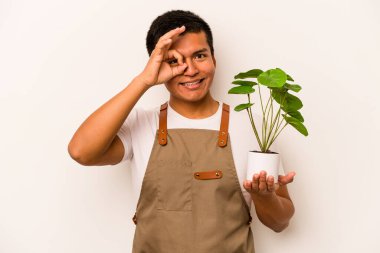 Genç bahçıvan İspanyol bir adam beyaz arka planda bir bitki tutuyor..