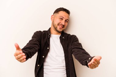 Beyaz arka planda izole edilmiş genç bir İspanyol hoş geldin ifadesi sergiliyor..