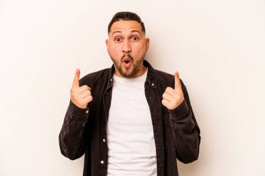 Beyaz arka planda izole edilmiş genç bir İspanyol ağzı açık bir şekilde yukarı işaret ediyor..