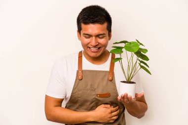 Genç bahçıvan İspanyol bir bitki tutuyor. Beyaz arka planda izole edilmiş. Gülüyor ve eğleniyor..
