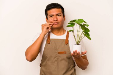 Genç bahçıvan İspanyol bir bitki tutuyor. Beyaz arka planda izole edilmiş. Parmakları dudaklarında sır saklıyor..