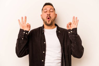 Beyaz arka planda izole olmuş genç İspanyol adam sıkı çalışma gününden sonra rahatlıyor, yoga yapıyor..