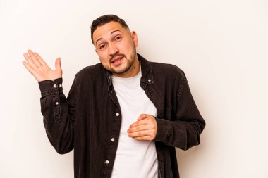 Beyaz arka planda izole edilmiş genç İspanyol bir adam. Kafası karışmış ve omuz silkiyor. Kopya alanını tutmak için..