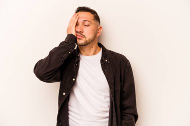 Beyaz arka planda izole edilmiş genç bir İspanyol. Çok yorgun ve uykulu. Elini başının üstünde tutuyor..