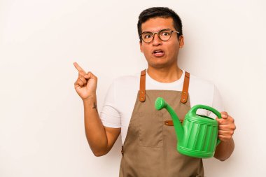 Genç bahçıvan elinde su kovası tutan İspanyol adam beyaz arka planda izole edilmiş ve yan tarafı işaret ediyor.