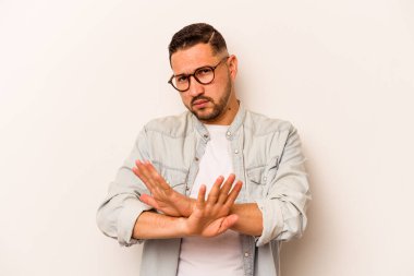 Beyaz arka planda izole edilmiş genç İspanyol bir adam inkar jesti yapıyor.