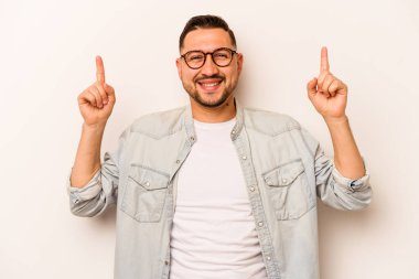 Beyaz arka planda izole edilmiş genç İspanyol bir adam iki parmağı da boş bir alan gösteriyor..