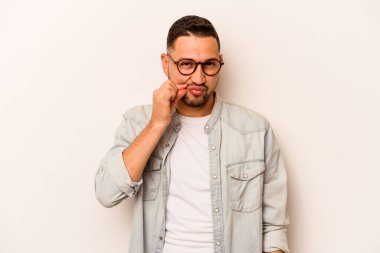 Beyaz arka planda izole edilmiş genç İspanyol adam parmakları dudaklarında bir sır saklıyor..