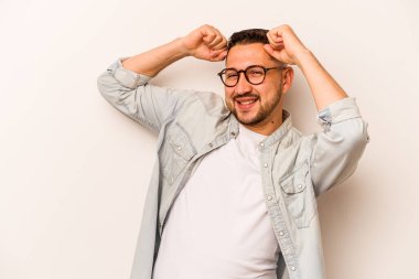 Beyaz arka planda izole edilmiş genç bir İspanyol özel bir günü kutluyor, atlıyor ve enerjiyle kollarını kaldırıyor..