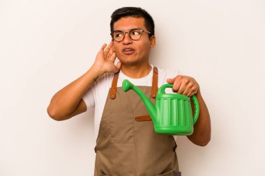Genç bahçıvan, elinde bir su bidonu olan İspanyol bir adam beyaz arka planda izole edilmiş bir şekilde bir dedikoduyu dinlemeye çalışıyor..