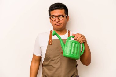 Genç bahçıvan İspanyol bir adamın elinde su kovası var. Beyaz arka planda izole edilmiş. Kafası karışmış, şüpheci ve kararsız..