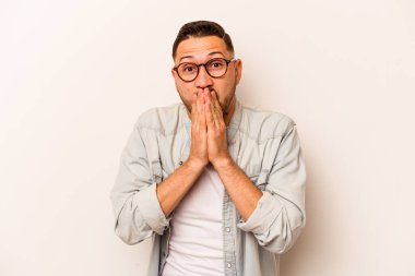 Beyaz arka planda izole edilmiş genç İspanyol adam elleri endişeli bir şekilde ağzı örtüyor..