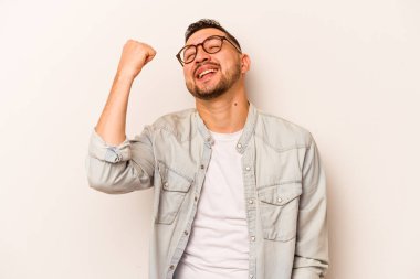 Beyaz arka planda izole edilmiş genç İspanyol bir adam zaferi, tutkuyu ve coşkuyu kutluyor, mutlu bir ifade..