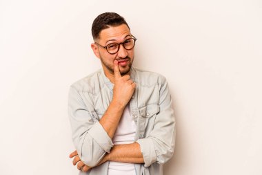 Latin kökenli genç bir adam beyaz arka planda izole edilmiş. Bir strateji planlıyor, bir iş yolu düşünüyor..