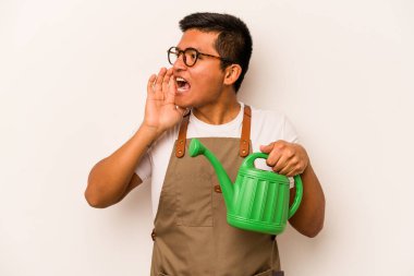 Genç bahçıvan İspanyol bir su bidonu tutuyor beyaz arka planda izole edilmiş bağırıyor ve avuç içini açık tutuyor..