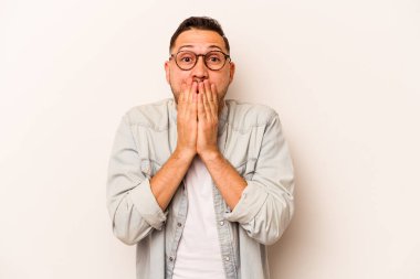 Beyaz arka planda izole edilmiş genç İspanyol adam şok olmuş, ağzı ellerle kaplanmış, yeni bir şey keşfetmeye hevesli..