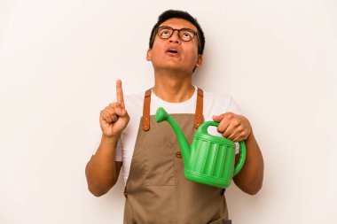 Genç bahçıvan İspanyol bir adam, beyaz arka planda izole edilmiş bir su bidonu tutuyor ve ağzı açık bir şekilde yukarı bakıyor..