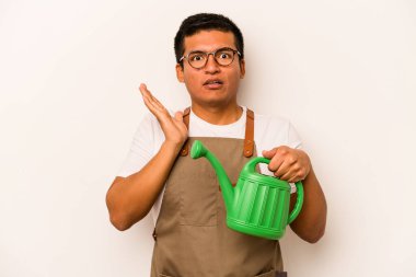 Genç bahçıvan, elinde su kovası olan İspanyol bir adam beyaz arka planda izole edilmiş, şaşırmış ve şok olmuştu..
