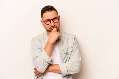 Genç İspanyol bir adam beyaz arka planda izole edilmiş düşünüyor, bakıyor, yansıtıyor, düşünüyor, bir fantezi kuruyor..