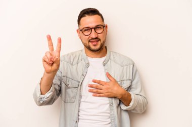 Genç İspanyol bir adam beyaz arka planda izole edilmiş yemin ediyor, elini göğsüne koyuyor..