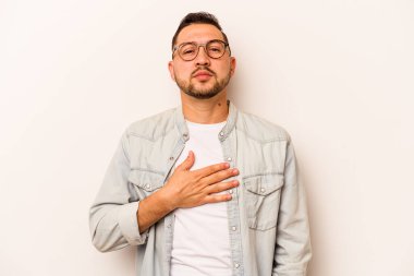 Genç İspanyol bir adam beyaz arka planda izole edilmiş yemin ediyor, elini göğsüne koyuyor..