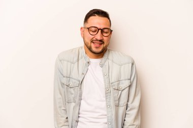 Beyaz arka planda izole edilmiş genç İspanyol adam gülüyor ve gözlerini kapıyor, rahatlamış ve mutlu hissediyor..