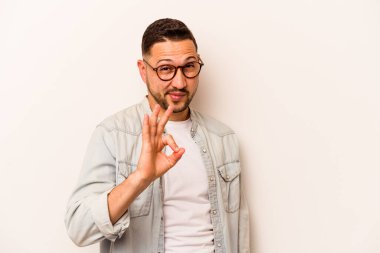 Beyaz arka planda izole edilmiş genç İspanyol bir adam bir göz kırptı ve elleriyle iyi bir jest yaptı..