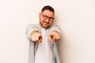 Beyaz arka planda izole edilmiş genç İspanyol adam parmaklarıyla ön tarafı işaret ediyor..