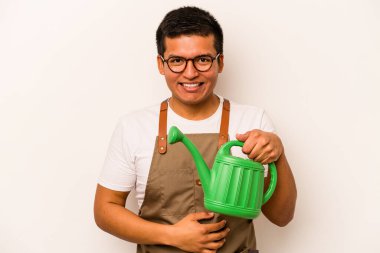 Genç bahçıvan İspanyol bir adam elinde bir su bidonu tutarken izole edilmiş beyaz arka planda gülüyor ve eğleniyor..