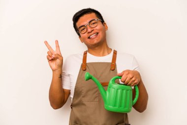 Genç bahçıvan, elinde su dolu bir teneke kutu tutan, neşeli ve kaygısız, parmaklarıyla barış sembolü gösteren İspanyol bir adam..