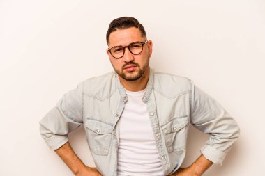 Genç İspanyol adam beyaz arka planda izole edilmiş üzgün, ciddi yüzlü, mutsuz ve hoşnutsuz..