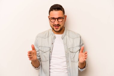 Beyaz arka planda izole edilmiş genç İspanyol adam iki eliyle bir şey tutuyor, ürün sunumu..