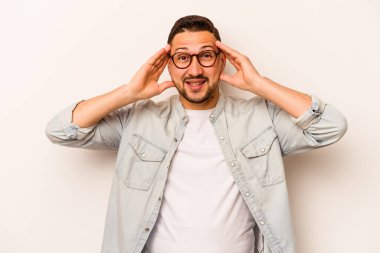 Latin kökenli genç bir adam beyaz arka planda izole edilmiş. Hoş bir sürprizle karşılaşıyor, heyecanlı ve el kaldırıyor..