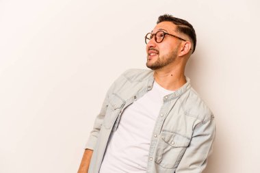 Beyaz arka planda izole edilmiş genç bir İspanyol. Rahatlamış ve mutlu bir şekilde gülüyor. Boynunda dişler var..