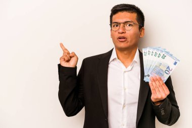 Latin kökenli genç bir iş adamı elinde banknotlar tutarken beyaz arka planda izole edilmiş.