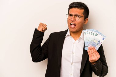 Latin kökenli genç bir iş adamı beyaz arka planda izole edilmiş banknotlar tutuyor zaferden sonra yumruğunu kaldırıyor, kazanan konsept.