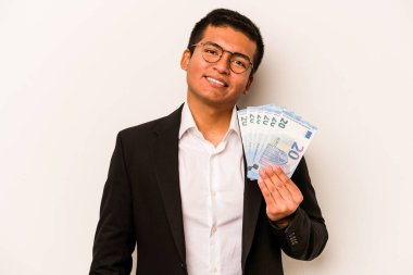Genç İspanyol iş adamı beyaz arka planda izole edilmiş banknotları tutuyor mutlu, güler yüzlü ve neşeli.