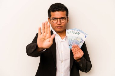 Genç İspanyol iş adamının elinde banknotlar var. Beyaz arka planda izole edilmiş. Elini uzatmış, dur işareti gösteriyor..