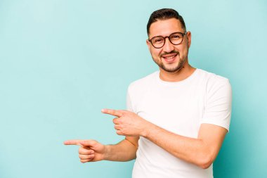 Mavi arka planda izole edilmiş genç bir İspanyol işaret parmaklarıyla işaret ederek heyecanlanıyor..