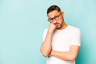 Mavi arka planda izole edilmiş, üzgün ve dalgın hisseden genç bir İspanyol fotokopi odasına bakıyor..