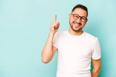 Mavi arka planda izole edilmiş genç İspanyol bir numara parmağıyla görünüyor..