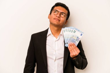 Genç İspanyol iş adamı beyaz arka planda izole edilmiş banknotları tutuyor hedeflerine ve amaçlarına ulaşmayı hayal ediyor.