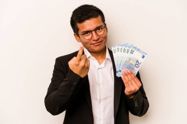 Latin kökenli genç bir iş adamı beyaz arka planda soyutlanmış banknotlar tutuyor. Sanki seni davet ediyormuş gibi seni işaret ediyor..