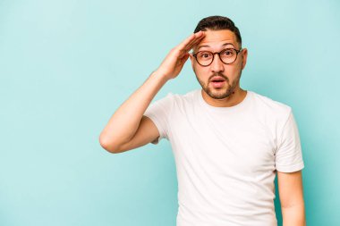 Mavi arka planda izole edilmiş genç bir İspanyol yüksek sesle bağırıyor, gözleri açık ve elleri gergin tutuyor..