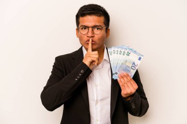 Genç İspanyol iş adamının elinde banknotlar var beyaz arka planda izole edilmiş ya sır saklıyor ya da sessizlik istiyor..