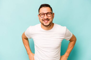 Genç İspanyol adam mavi arka planda izole edilmiş mutlu, güler yüzlü ve neşeli.