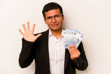 Genç İspanyol iş adamı banknotları elinde tutuyor beyaz arka planda izole edilmiş gülümseyen beş numarayı parmaklarıyla gösteriyor..
