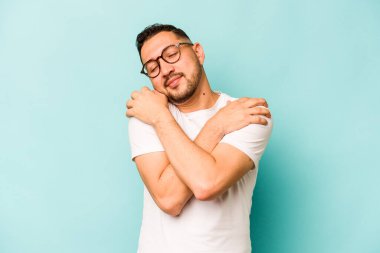 Genç İspanyol adam mavi arka planda yalnızdı. Kucaklaşma, kaygısız gülümseme ve mutluluk..