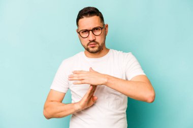 Mavi arka planda izole edilmiş genç İspanyol bir adam bir mola hareketi gösteriyor..