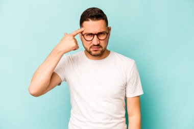 Mavi arka planda izole edilmiş genç İspanyol adam işaret parmağıyla bir hayal kırıklığı gösteriyor..